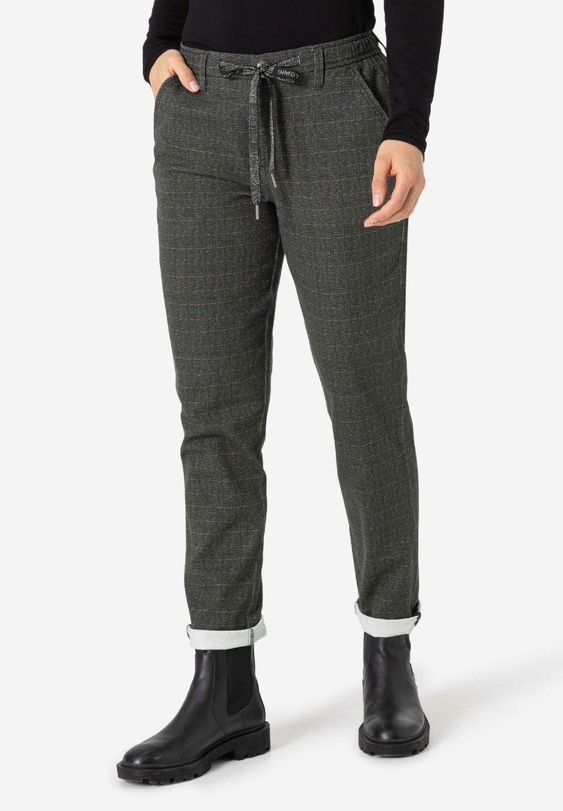 Dark green plaid trousers with an elastic waistband, drawstring detail, and rolled cuffs, paired with black ankle boots.