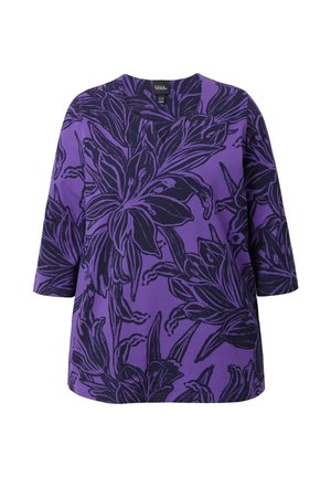 Paarse top met grote donkere bloemenprint, driekwart mouwen en een ronde halslijn.