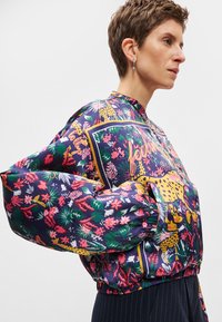 Veste bomber colorée et à motifs avec un design floral et léopard. Comprend une taille et des poignets élastiqués, fabriquée en tissu lisse et brillant.