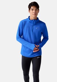 Herren langärmliges Sportoberteil in Blau mit einem halben Reißverschluss, strukturiertem Stoff und Daumenlöchern, kombiniert mit schwarzen enganliegenden Leggings.