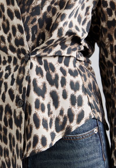 Blusa in stampa leopardata di un beige chiaro con macchie scure, dotata di colletto, chiusura a bottoni e orlo curvo.