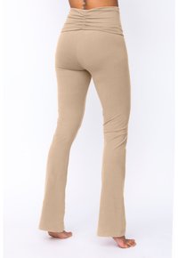 Beige utställda leggings med en hög, rynkad midja, tillverkade av ett mjukt, stretchigt tyg. Slät textur med en figurnära silhuett.