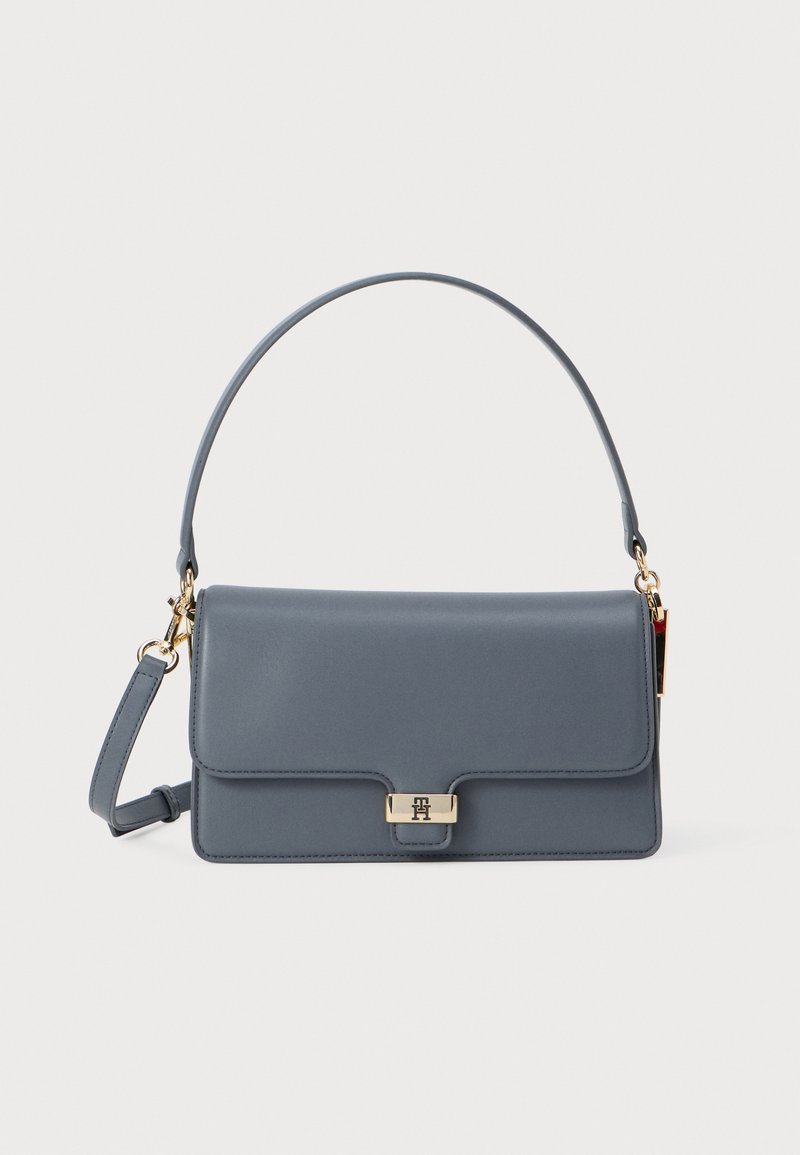 Szürke bőr kézitáska, fedelezett kialakítással, arany színű fémrészekkel és levehető pánttal. Simább textúra, elöl logóval kiemelve.