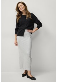 Zwarte cardigan met knopen, grijze lange rok en zwarte ballerina's. De cardigan heeft geribbelde boorden; de rok is glad met een aansluitende pasvorm.