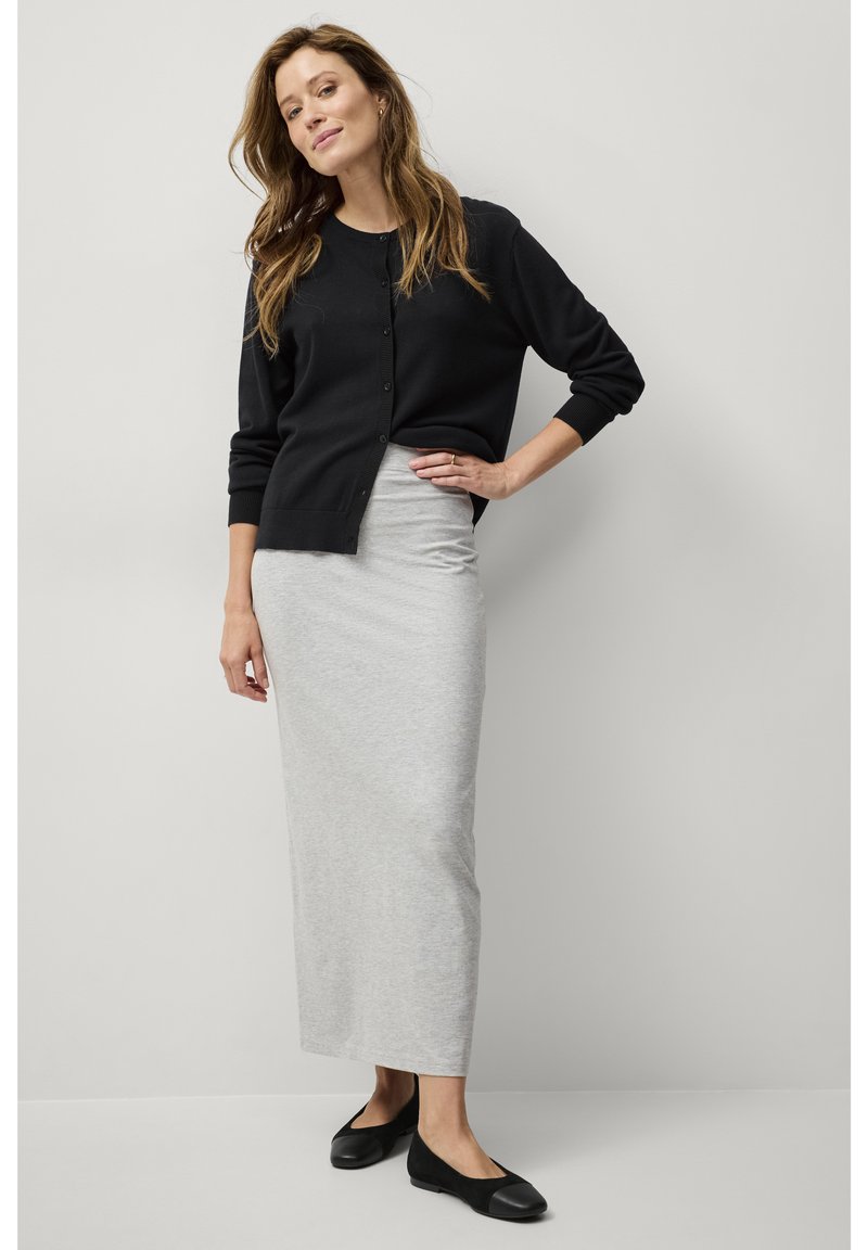 Zwarte cardigan met knopen, grijze lange rok en zwarte ballerina's. De cardigan heeft geribbelde boorden; de rok is glad met een aansluitende pasvorm.