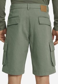 Gröna cargoshorts i en bomullsblandning. Har flera sidofickor och en läderlapp på bakre midjan.