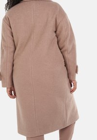 Lys pink uldblanding frakke, lang med lige snit, stor krave og sidelomme. Har tekstureret stof og minimal syning.