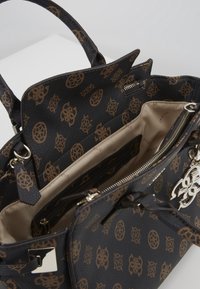 Sac à main en cuir noir texturé avec un motif de logo marron, compartiments intérieurs et un accent en métal argenté. Détail de fermeture éclair visible.