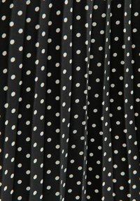 Black pleated fabric with white polka dots, featuring a smooth texture and consistent pattern throughout.