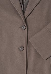 Un manteau en laine marron avec un col à revers, deux boutons et une doublure intérieure lisse. La texture du tissu présentée est douce avec une finition soignée.