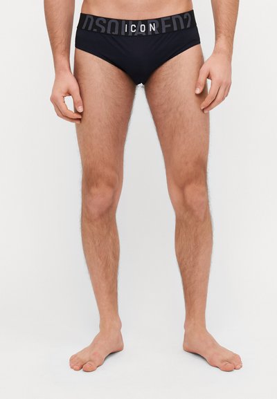 Black swim briefs with a contrasting gray elastic waistband featuring the text "ICON" and "DSQUARED2" in large lettering. Smooth texture.