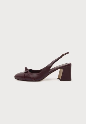 Σκούρο μπορντό ψηλοτάκουνο παπούτσι slingback με μυτερή μύτη, λεπτομέρεια με σταυρωτό λουράκι, μικρό φιόγκο και ρυθμιζόμενο λουράκι στον αστράγαλο σε λευκό φόντο.