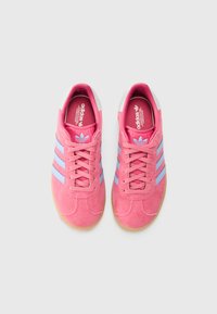 Rosa semskesneakers med lyseblå striper, hvite hælakkenter og såler i gummi. Har snøring og merkede såler.