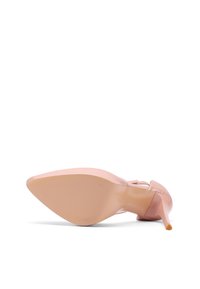 Scarpa beige in vernice con tacco alto e punta affilata, caratterizzata da una suola testurizzata e un accento arancione sulla punta del tacco.