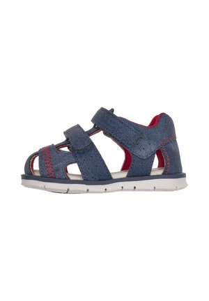 Marineblå sandal med denimtekstur, med to velcrolukninger, åben design, røde accenter og en fleksibel hvid sål.