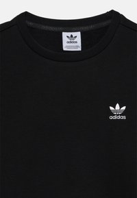 Svart sweatshirt i mjukt tyg med rund halsringning. Har en vit Adidas-logotyp broderad på vänster bröst.