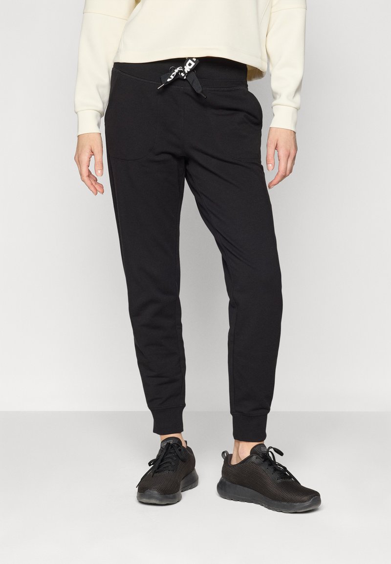 Svarte joggebukser med elastisk midje og snor, med sidelommer. Sammen med svarte mesh joggesko.