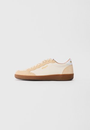 Beige und weiße Low-Top-Sneaker mit brauner Sohle, beige Wildleder-Details, beige Schnürsenkeln und "Blauer"-Branding an der Seite und der Ferse.