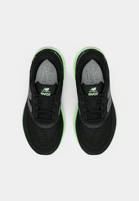 Must musta musta New Balance Evoz jooksujalatseid mustade sääremärgiga roheliste talladega, vaadatuna ülevalt valgel taustal.