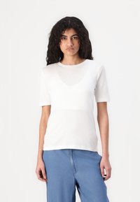 Weißes Kurzarm-T-Shirt mit rundem Ausschnitt, hergestellt aus einem glatten, leichten Stoff. Taillierte Form mit einem subtilen transparenten Overlay-Effekt.