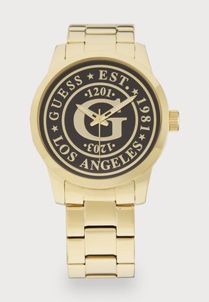 Guldfarvet rustfrit stål ur med en sort urskive, der viser 'GUESS'-logoet, etableringsdato, og tydelige markeringer. Glat link armbåndsdesign.