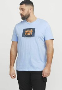 Heleheles helesinine puuvillane t-särk, mille ees on julge tumesinine ja oranž "JACK & JONES" logo. Lühikesed varrukad, standardne lõige, sile tekstuur.