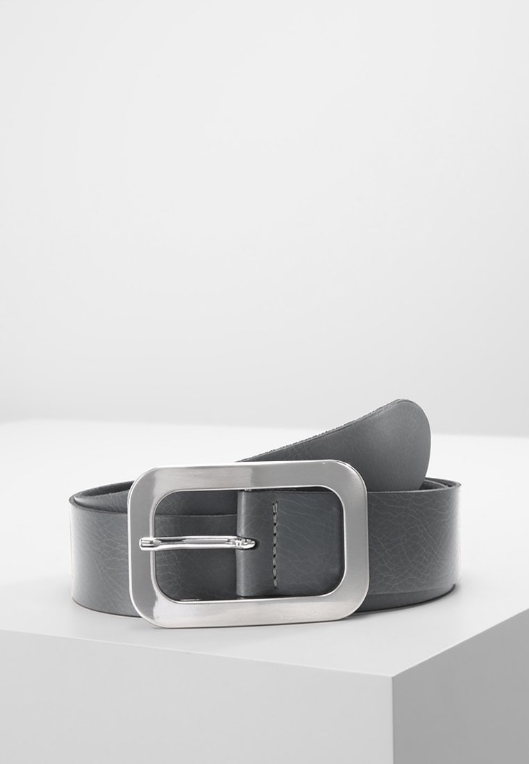Ceinture en cuir gris foncé avec une large boucle rectangulaire en argent, placée enroulée sur une surface blanche.