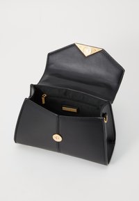 Borsa a tracolla in pelle nera con una patta esagonale, hardware dorato e chiusura a pulsante magnetico. L'interno presenta una tasca con zip e fodera.