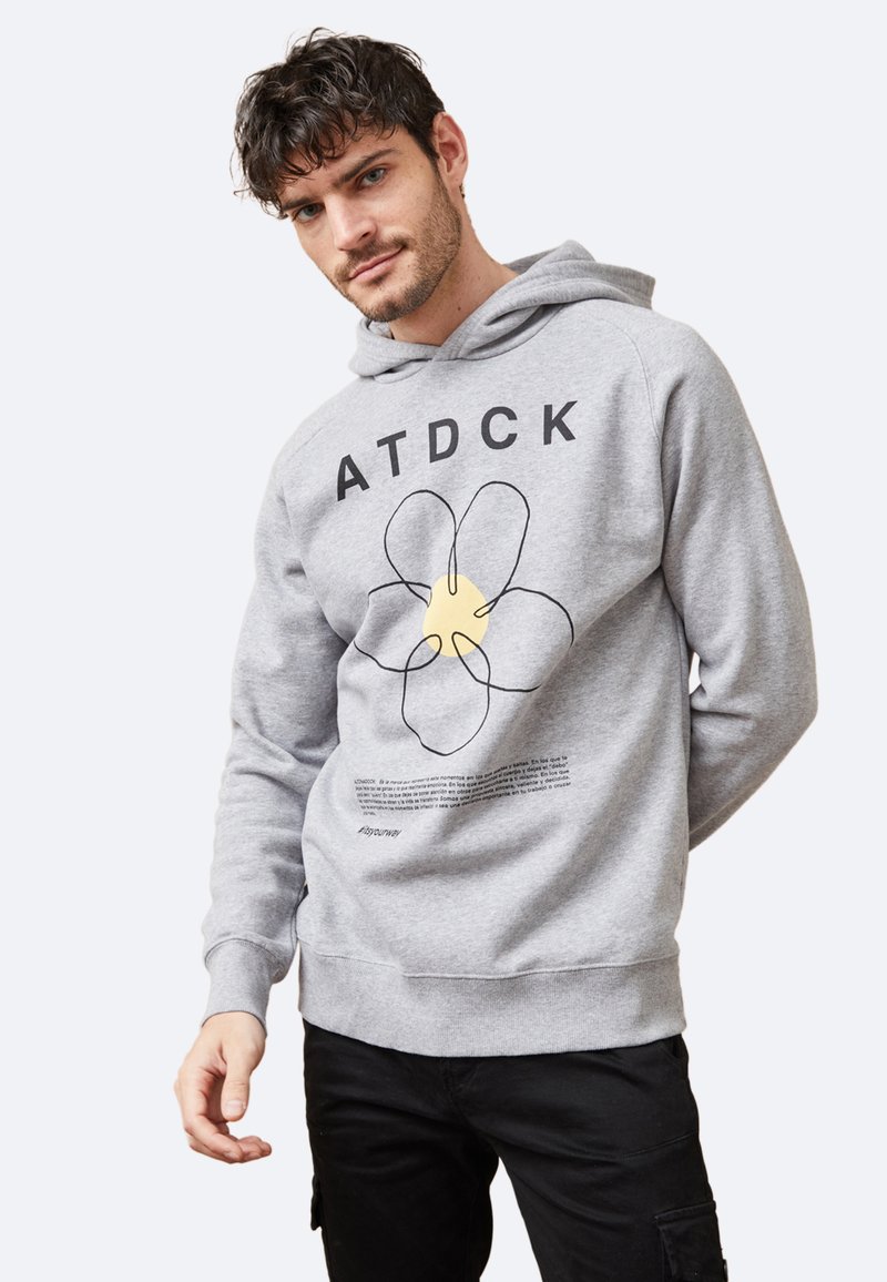 Sudadera gris con un gran diseño gráfico floral y texto. El material es suave, con un ajuste holgado y un bolsillo tipo canguro.