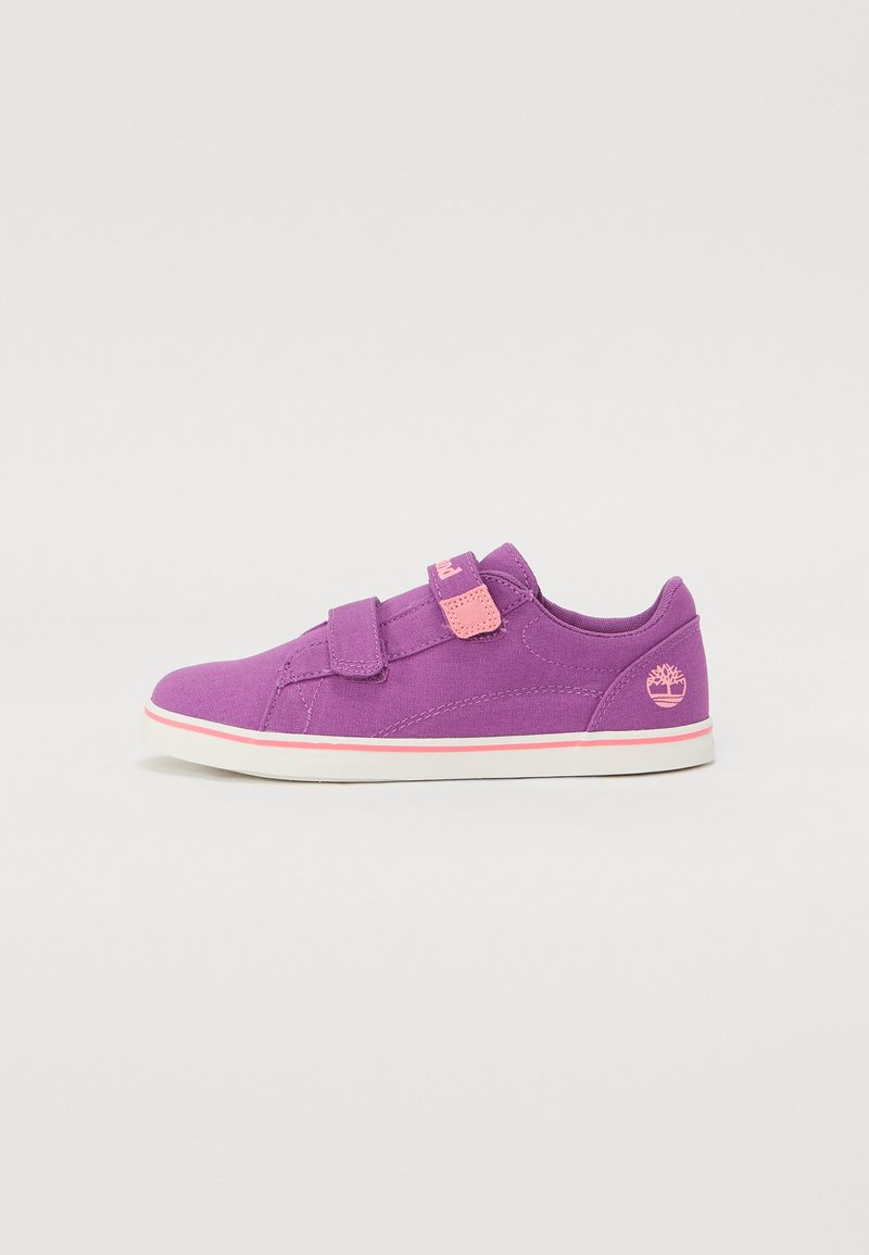 Purple canvas sneakers with Velcro straps, white rubber sole, and pink accents. Features a logo on the heel and a textured upper.