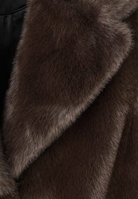 Bruine nep bont stof met een zachte, pluizige textuur; heeft een gladde glans en een gelaagd ontwerp, wat zorgt voor een warme en gezellige uitstraling.