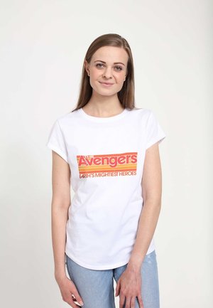 Hvid kortærmet t-shirt med et farverigt "Avengers" grafik med orange og rød tekst, parret med lyseblå jeans.