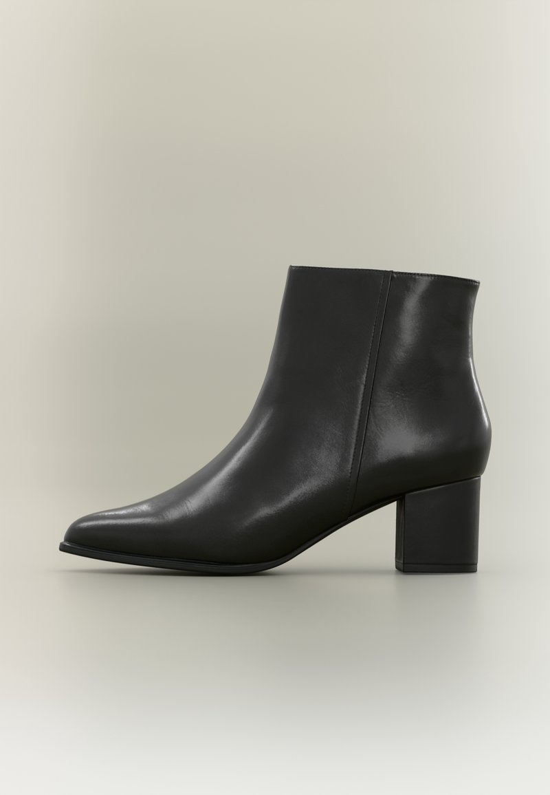 Bottine en cuir noir avec bout pointu et talon bloc sur fond neutre.