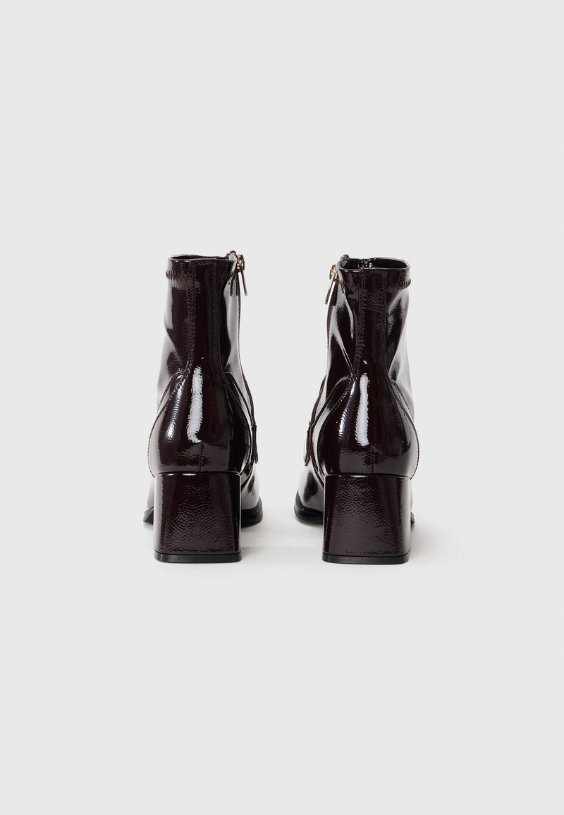 Stivali alla caviglia in pelle verniciata nera con tacco quadrato, dotati di chiusura con zip sul retro e leggero arricciamento ai lati.