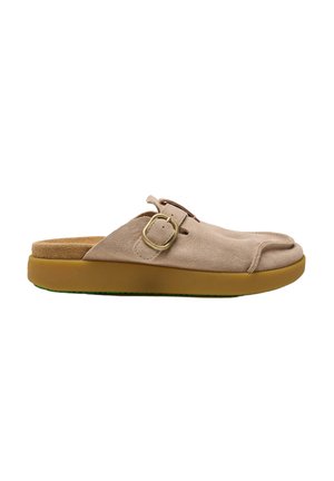Zapato beige de ante tipo slip-on con una hebilla redonda dorada y una suela gruesa de goma marrón, mostrado de perfil.