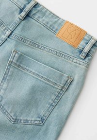 Lichtblauwe denim jeans met een gestructureerde afwerking, voorzien van een achterzak en een rechthoekige tan leren patch met logodetail.