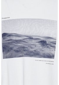 Hvid bomulds T-shirt med et blåt stribet grafik af bakker og tekst nedenfor i to linjer: "Det er ikke hvad du ser på, der betyder noget, det er hvad du ser."