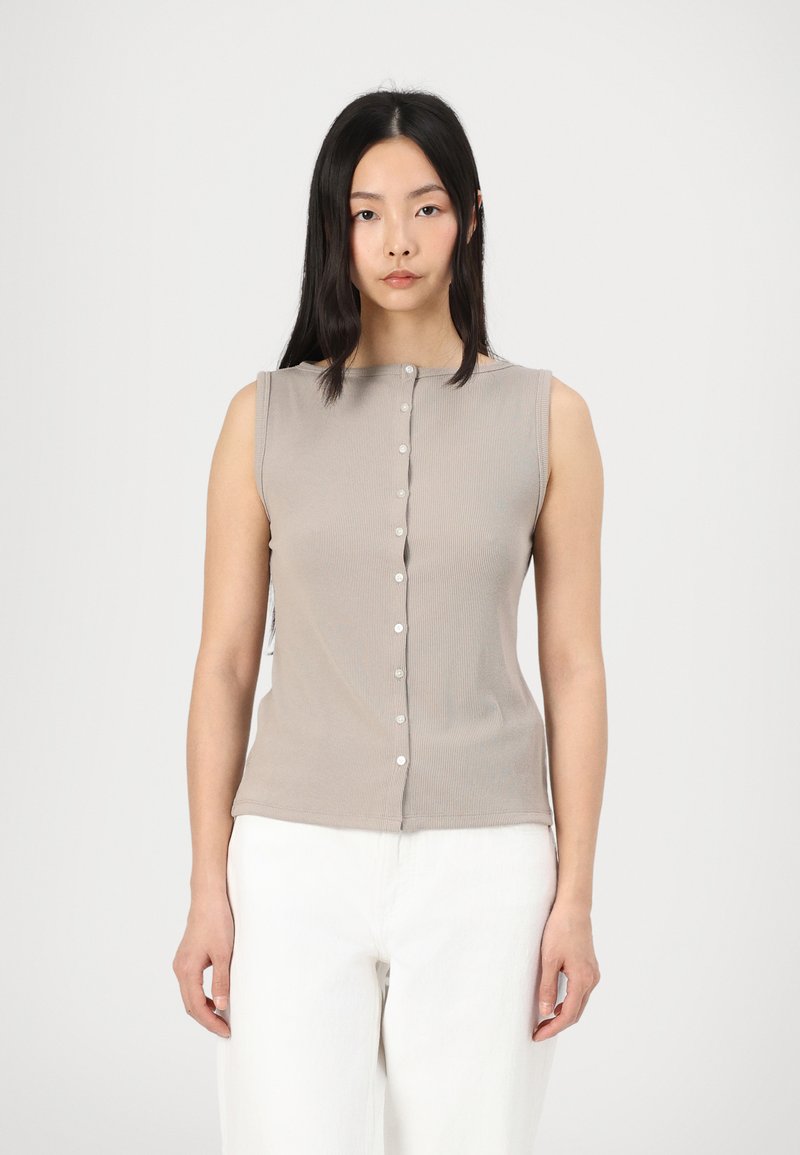 Haut beige sans manches en rib avec un col rond et une fermeture à boutons sur le devant, agrémenté de petits boutons blancs ; texture lisse.