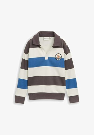 Chemise de rugby à manches longues avec larges rayures horizontales en crème, bleu et brun foncé, ornée d'un petit patch rond cartoon sur la poitrine.