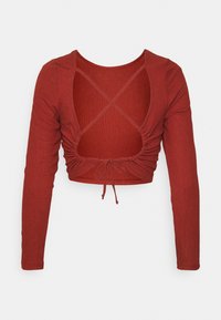 Maglia rossa a manica lunga con scollatura a barchetta e design con incrocio sulla schiena. Dettaglio arricciato con coulisse all'orlo.