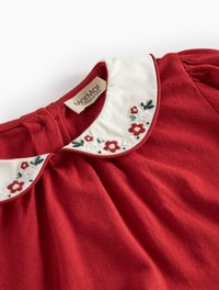 Rochie roșie cu o guler alb, împodobit cu broderie florală. Material moale cu detalii plisate la gât și umeri. Etichetă vizibilă.