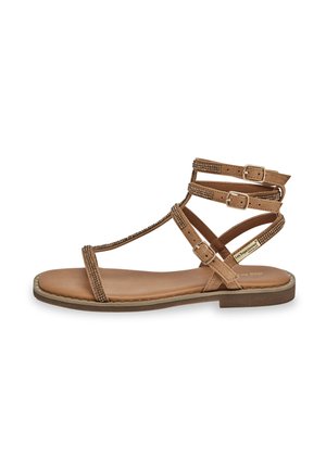 Sandales plates brunes avec plusieurs sangles accentuées de métal, une semelle plate et une semelle intérieure texturée. Les boucles permettent un ajustement réglable.