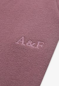 Pleteni pulover od mekog, mauve materijala; sadrži suptilnu teksturu i izvezeni "A & F" logo u boji koja odgovara materijalu.