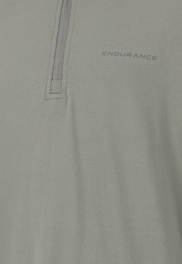 Ljusgrön polo tröja med halvmatch, texturerad tyg och subtil logotyp "ENDURANCE" i grått på bröstet.