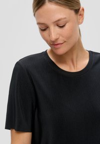 Czarny prążkowany top z krótkim rękawem, z okrągłym dekoltem, charakteryzujący się miękką teksturą i dopasowanym krojem.