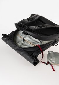 Zaino nero con design a piegatura, dotato di una fodera interna argentata e di un tirazip rosso. Include una piccola pochette coordinata.