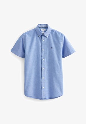 Camicetta a maniche corte, di colore azzurro chiaro, in tessuto di cotone con colletto. Presenta bottoni bianchi e un piccolo logo ricamato sul petto.