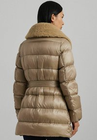 Opblazende jas in metallic taupe met een pluche beige kraag, een ceintuur om de taille en een quilt-design. Bevat een zachte, glanzende textuur.