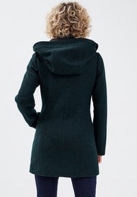 Dark green, textured coat featuring a hood, fitted design, and long sleeves. Back view shows seam details and a mid-thigh length.