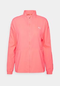 Koraliowo-różowa sportowa kurtka zapinana na zamek z długimi rękawami, stojącym kołnierzem, elastycznymi mankietami, bocznymi kieszeniami oraz białym logo Pumy na piersi.